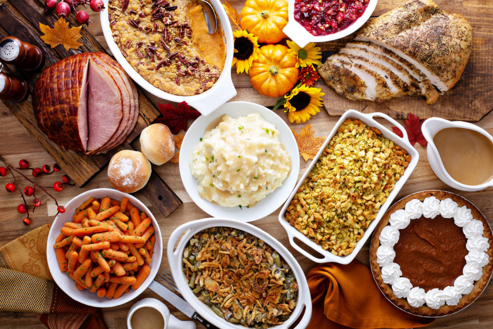 Thanksgiving table with roasted turkey, sliced ham and side dishes