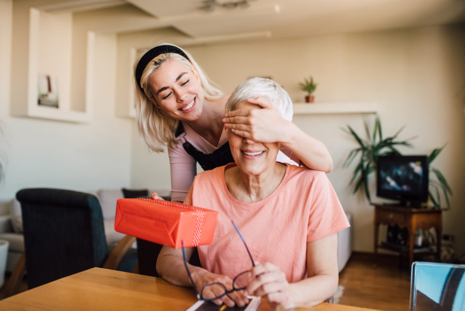 Older woman receiving a Mother's Day gift from her happy daughter