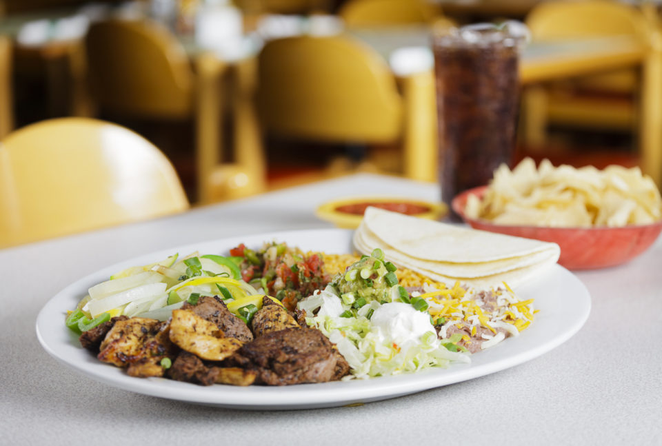 A plate of fajita tacos with a soda.